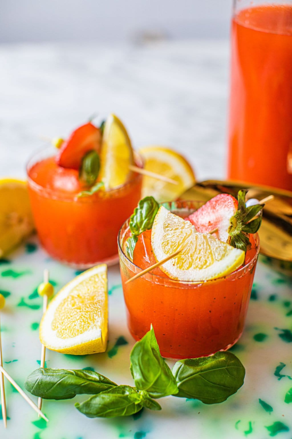 strawberry and basil lemonade garnished with strawberry and fresh lemon wedge