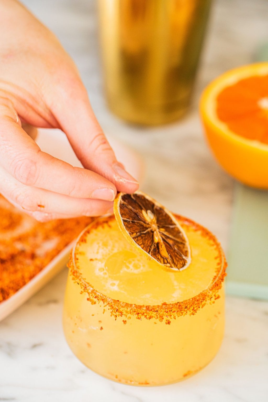 garnishing an orange margarita with a slice of the fruit