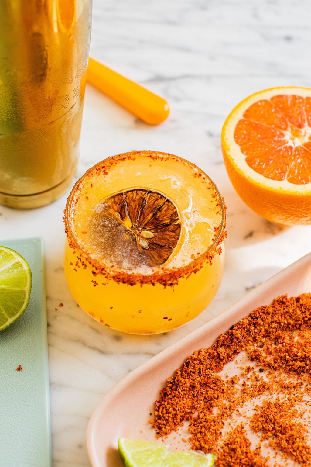 orange margarita with tajin around the rim and orange slice garnish on top