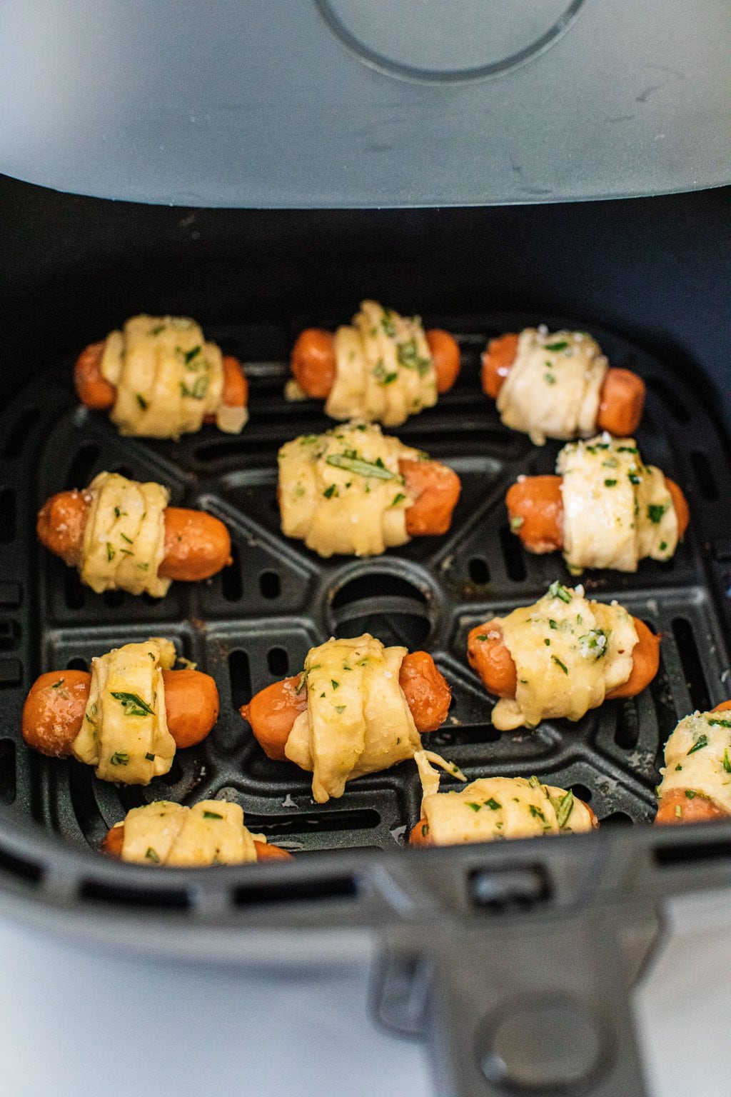 four rows of pigs in a blanket in the air fryer basket