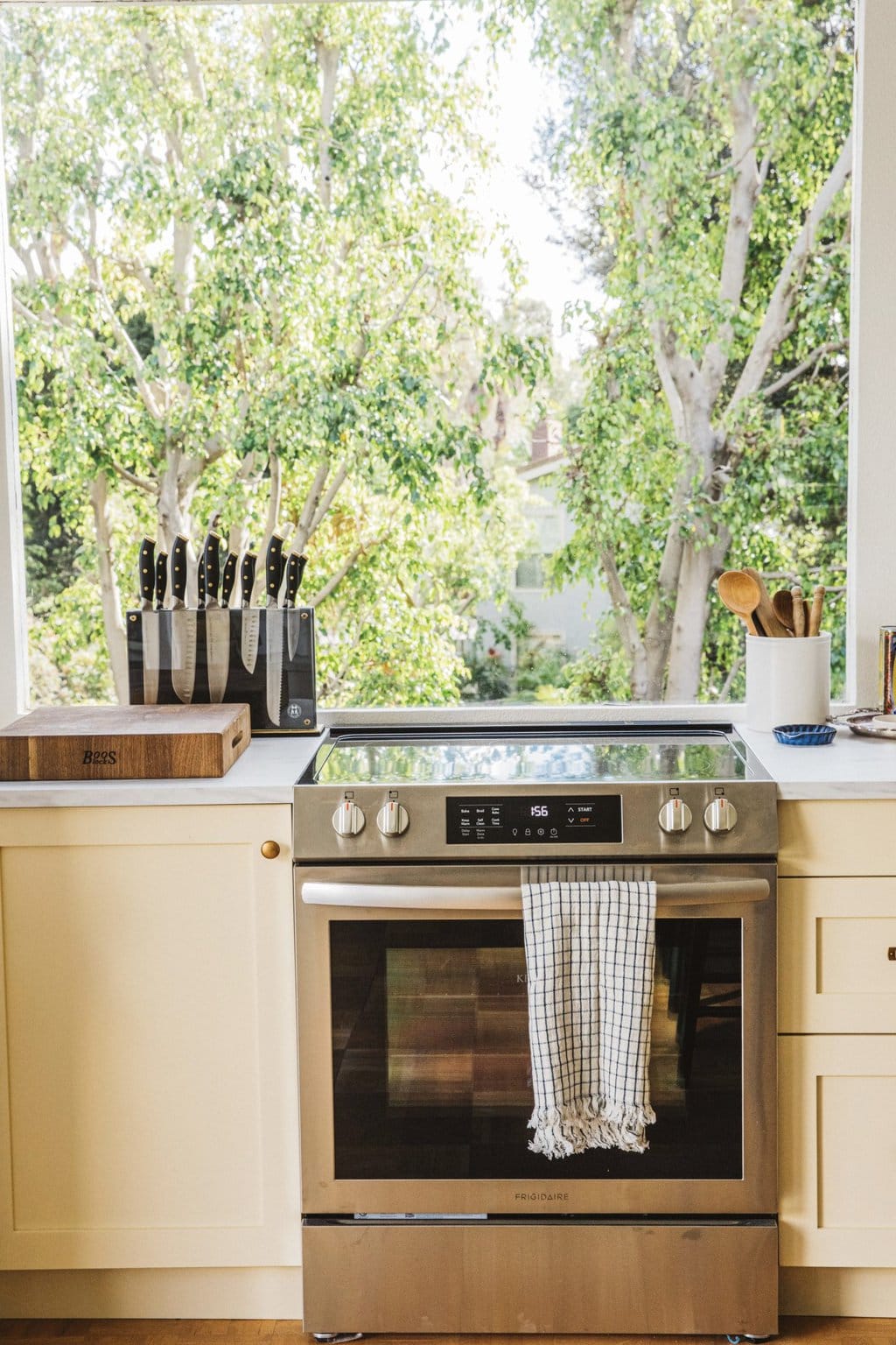 stainless steel stove in front of a large kitchen window 