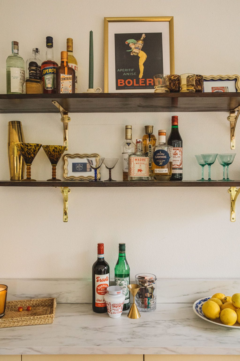 two wooden open shelves filled with liquor bottles and glassware 