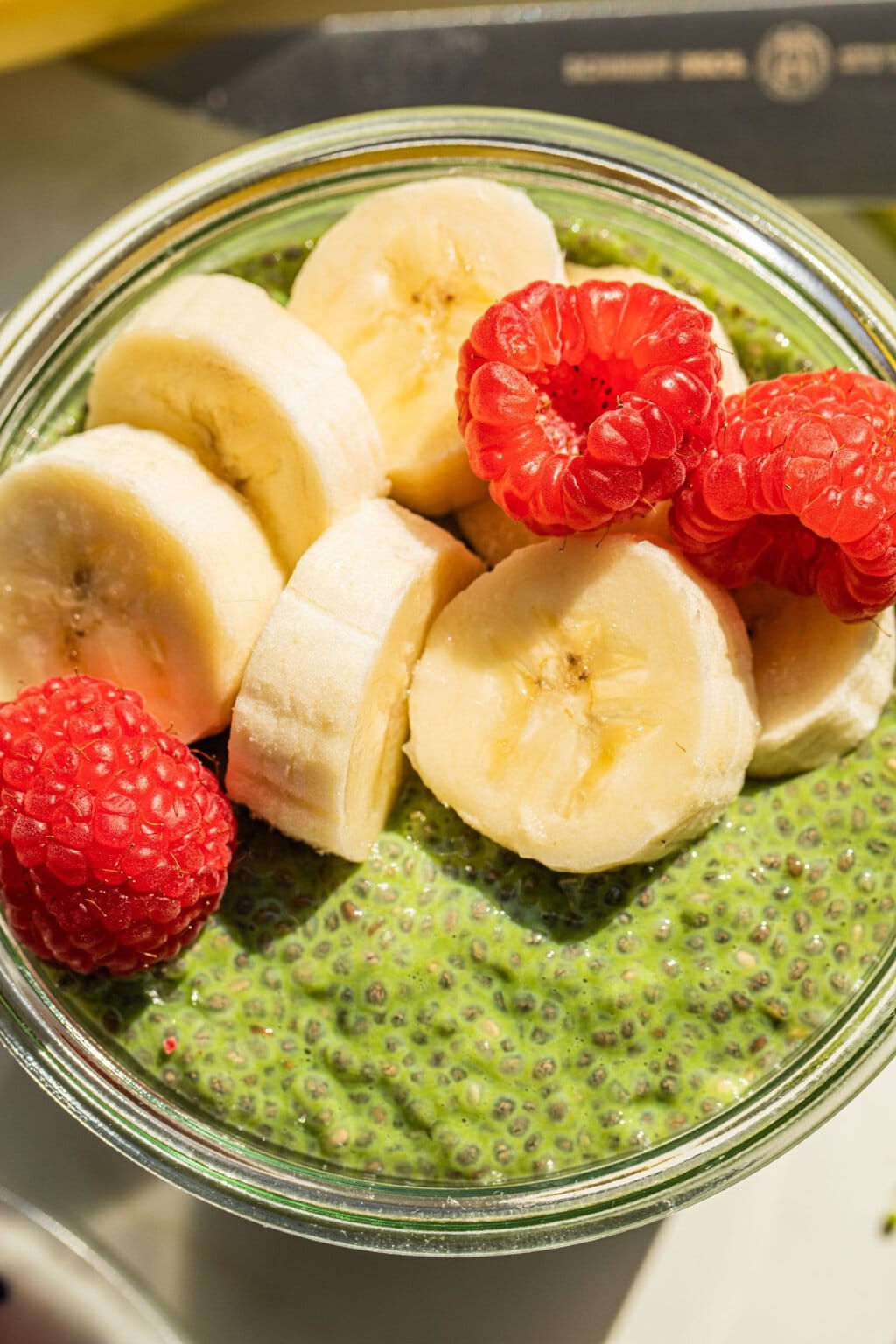 a bowl of matcha chia seed pudding with bananas and raspberries on top