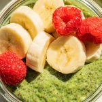 a bowl of matcha chia seed pudding with bananas and raspberries on top