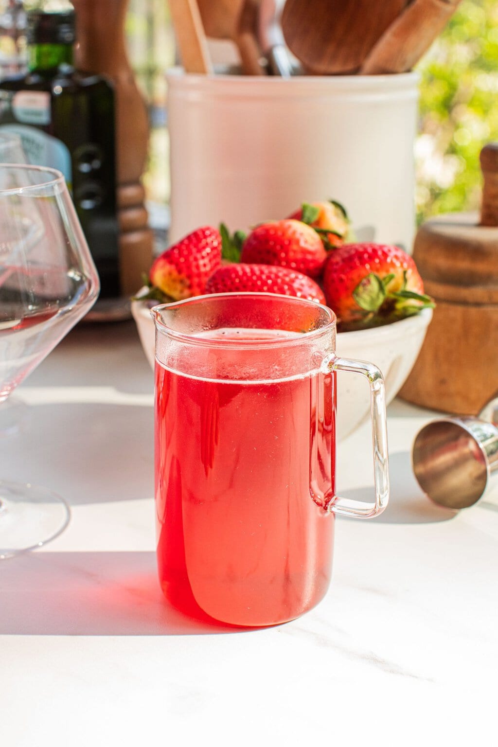 a glass pitcher of strawberry simple syrup