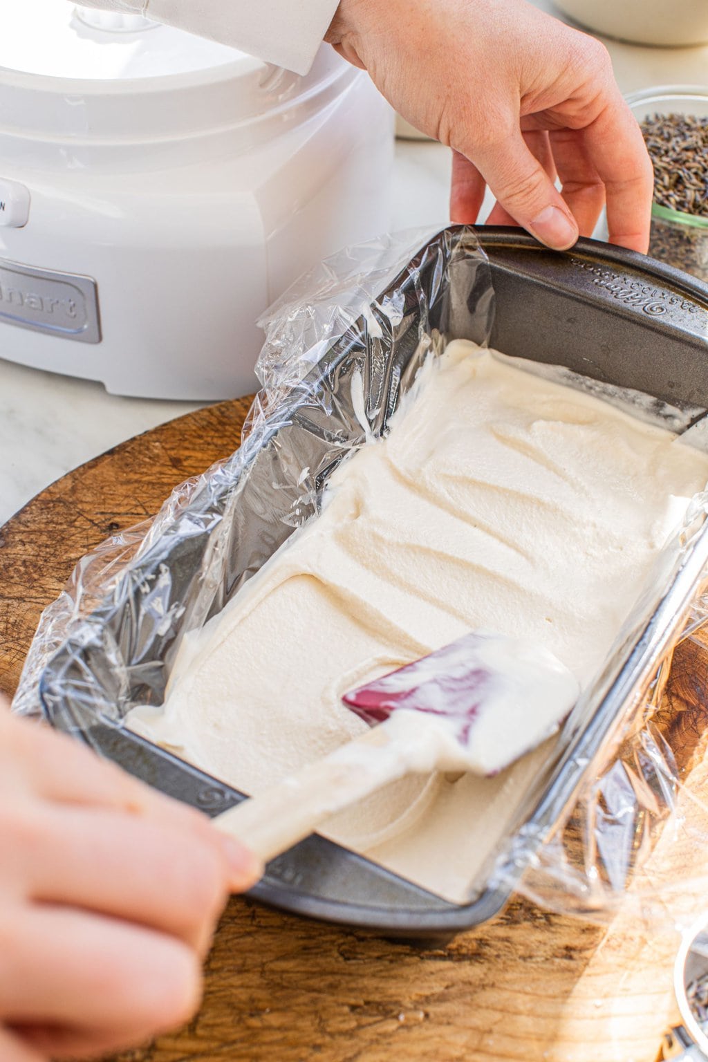 a baking loaf full of ice cream with a spatula smoothing it out