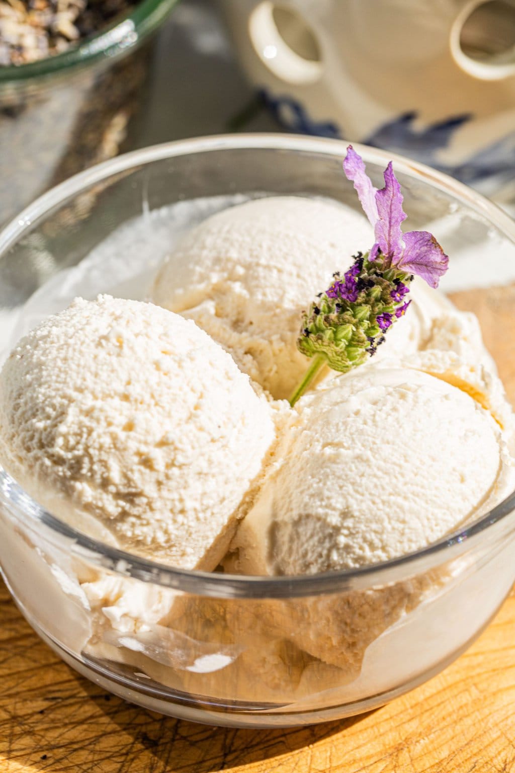 three dollops of lavender ice cream with honey in a bowl and a sprig of lavender garnishing the top