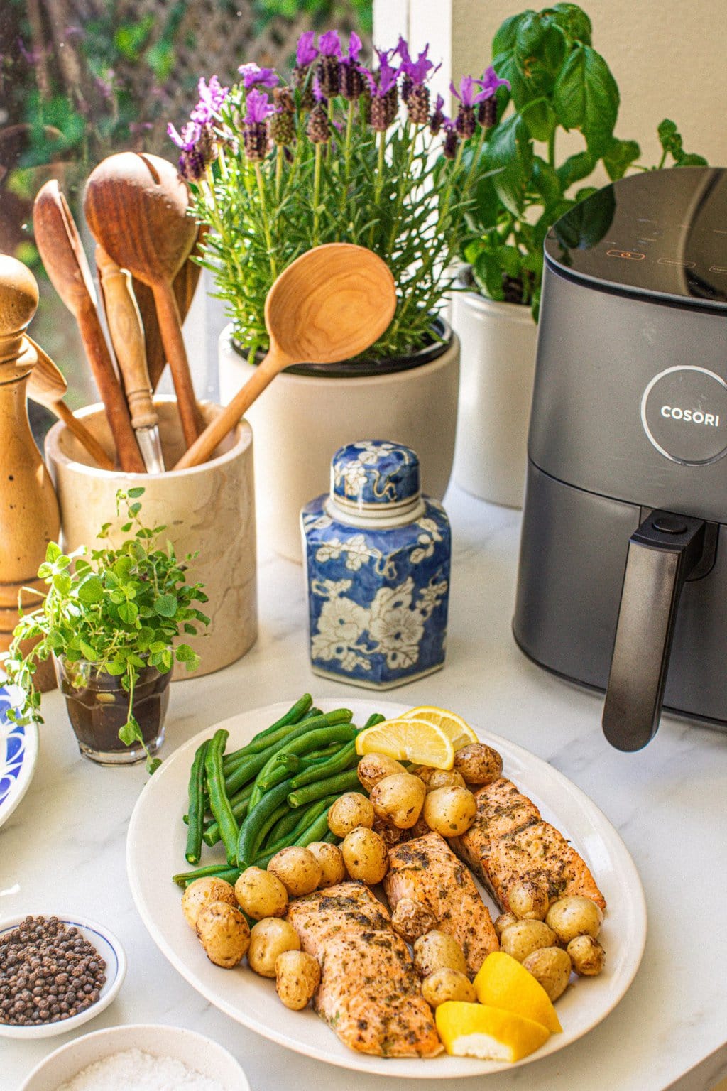 salmon made in the air fryer with potatoes and green beans on the side, garnished with lemon wedges