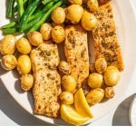 a white plate full of air fryer salmon with potatoes and green beans and text overlay at the bottoms