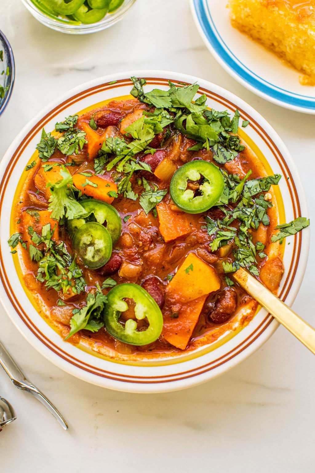 a bowl of veggie chili with jalapenos and herbs on top