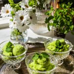 three glasses of pear sorbet on a silver serving tray with white and green flowers in the background