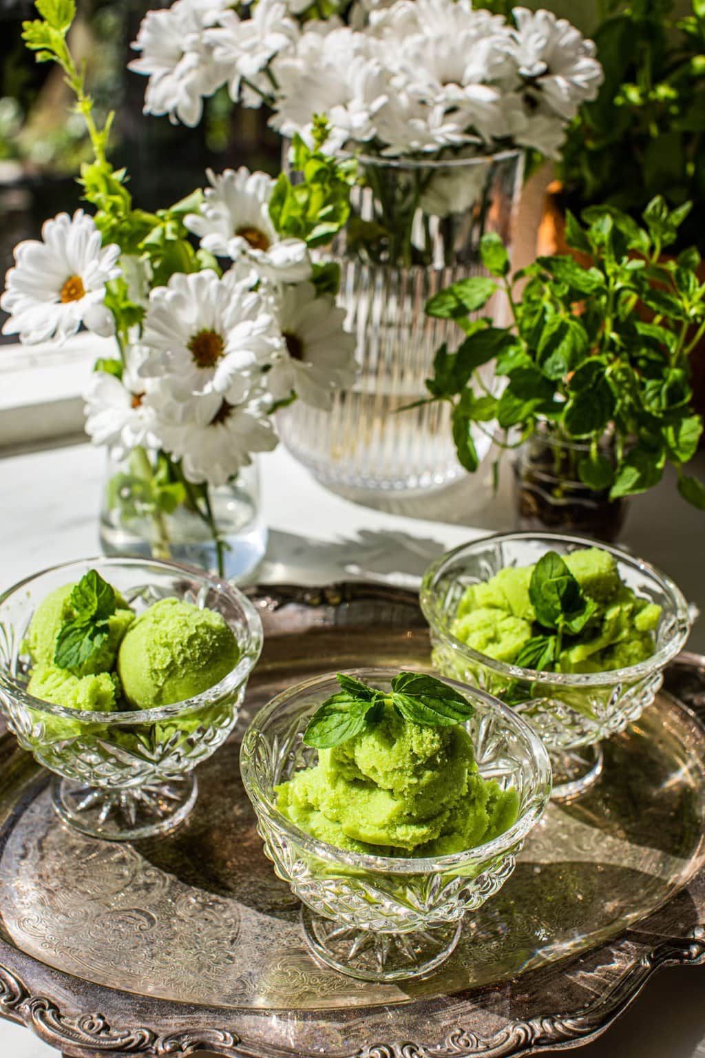 three glasses of pear sorbet on a silver serving tray with white and green flowers in the background