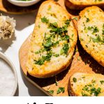 homemade garlic bread on a wooden serving board with fresh parsley and text overlay