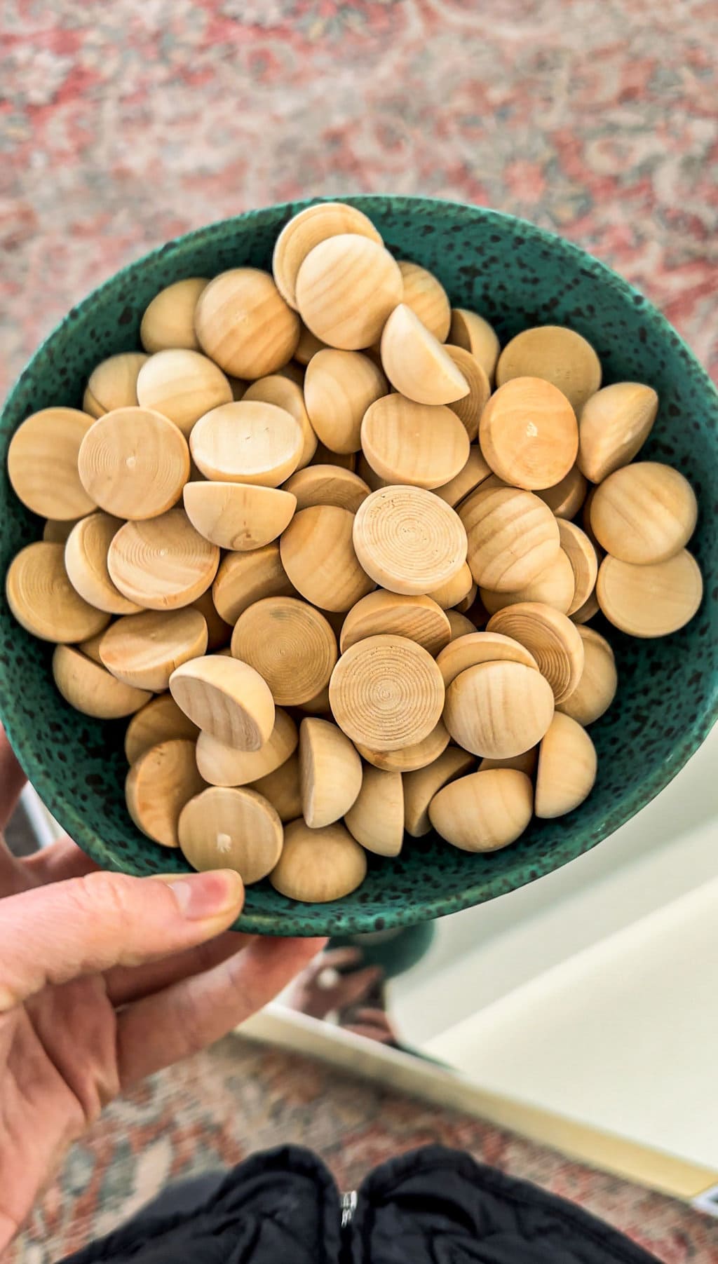 a blue bowl filled with many half wooden spheres 