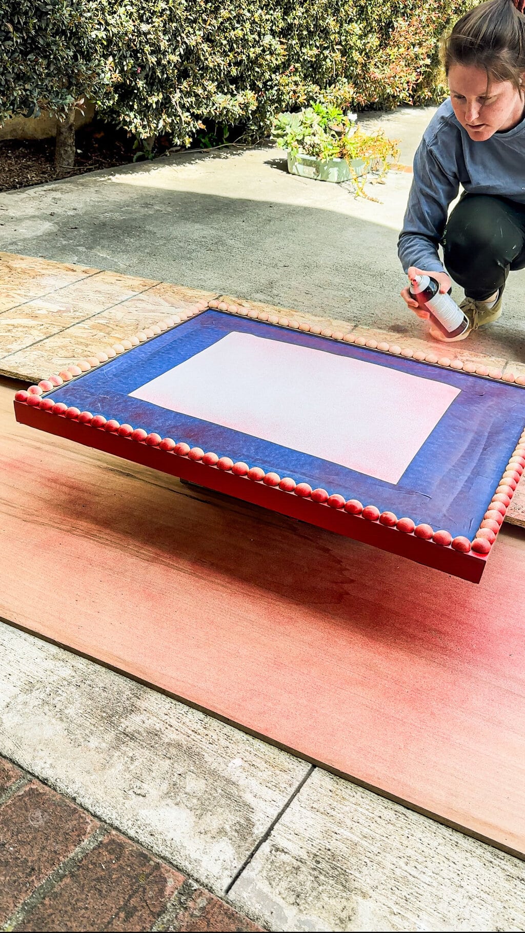 Elizabeth spray painting the bobbin mirrors edge with red spray paint 