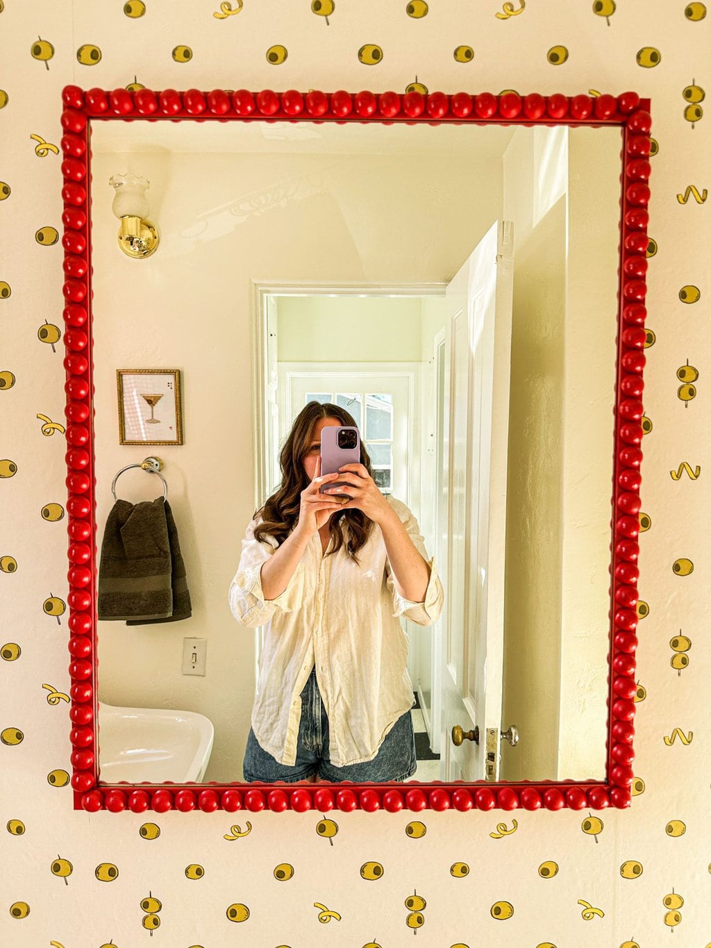 elizabeth taking a selfie in the diy red bobbin mirror on top of olive and lemon white wallpaper 