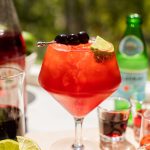 a cherry spritz in a glass with cherries and a lime wedge on top