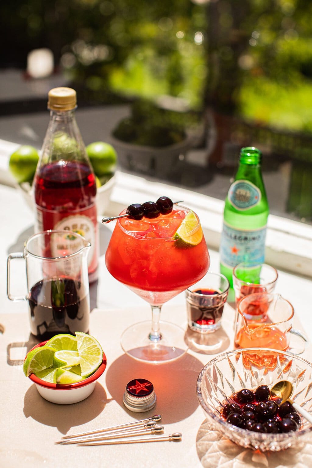 a cherry spritz surrounded by the ingredients