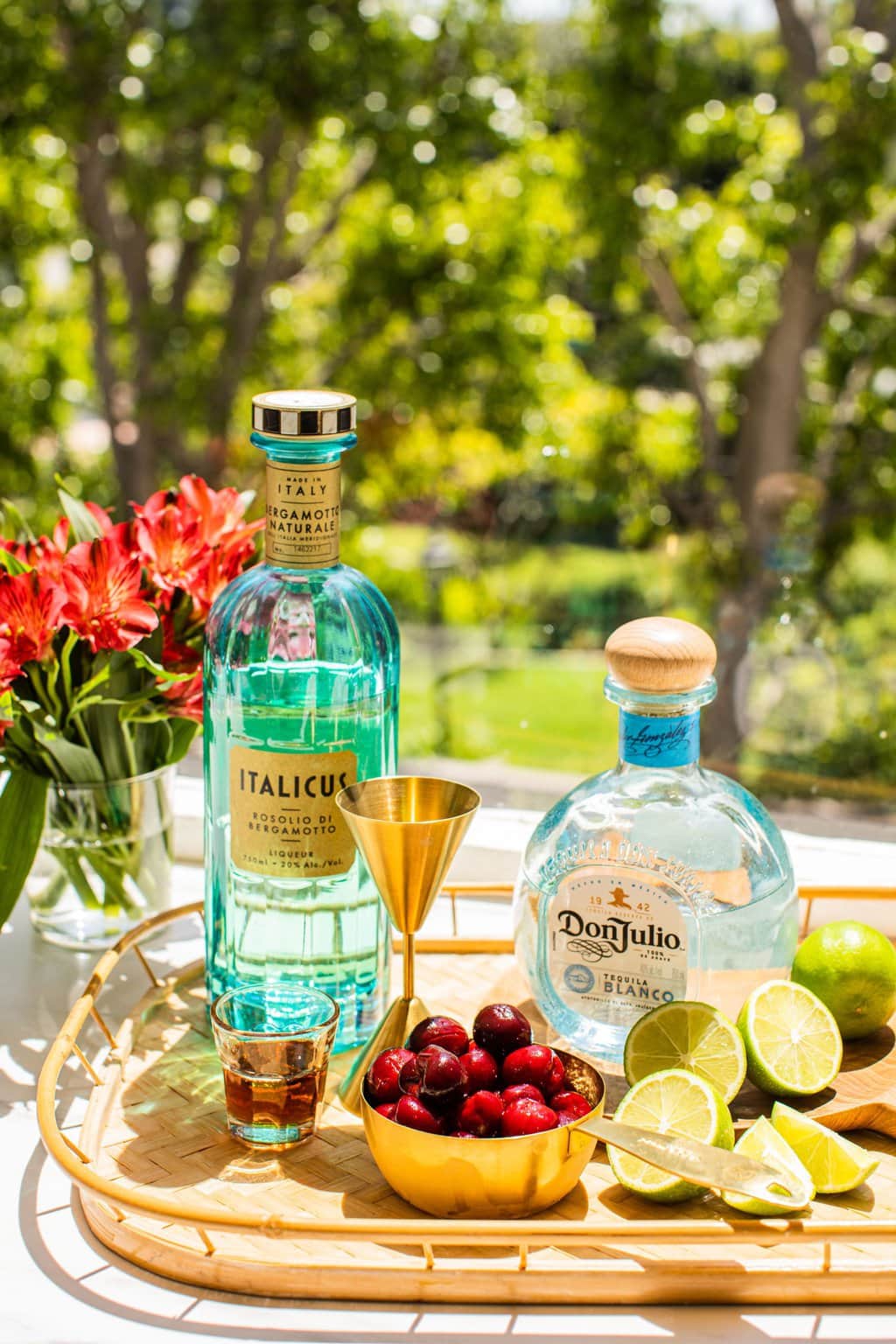 a bottle of italicus, a bowl of cherries, a bottle of don julio, chopped limes, and agave