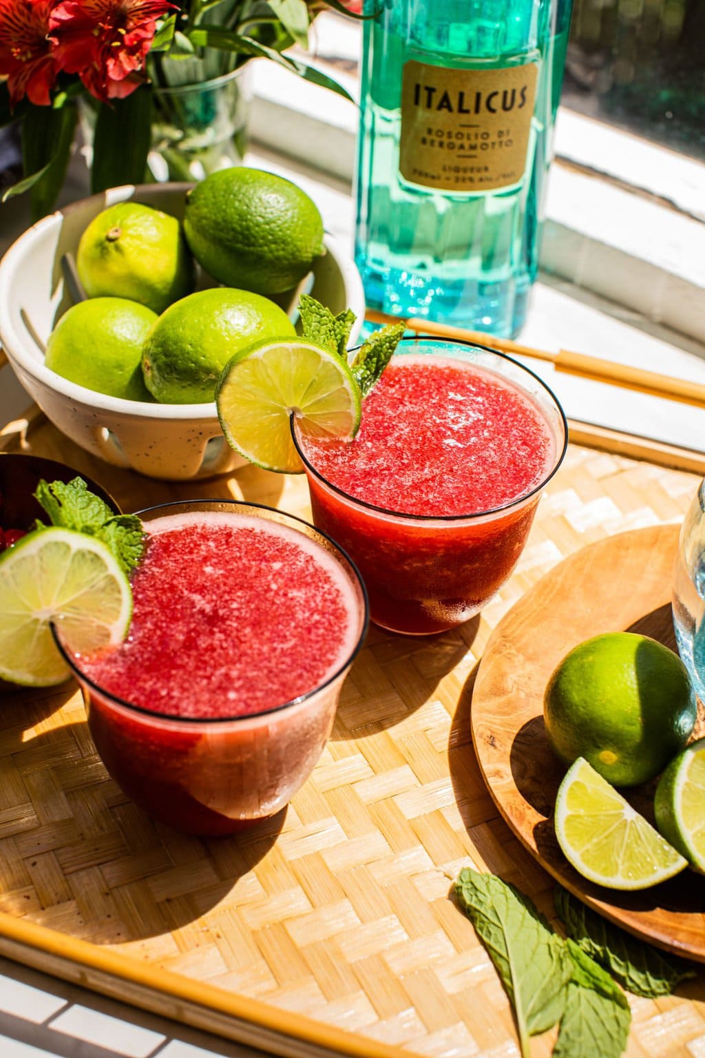 two glasses of cherry margaritas with lime wedges