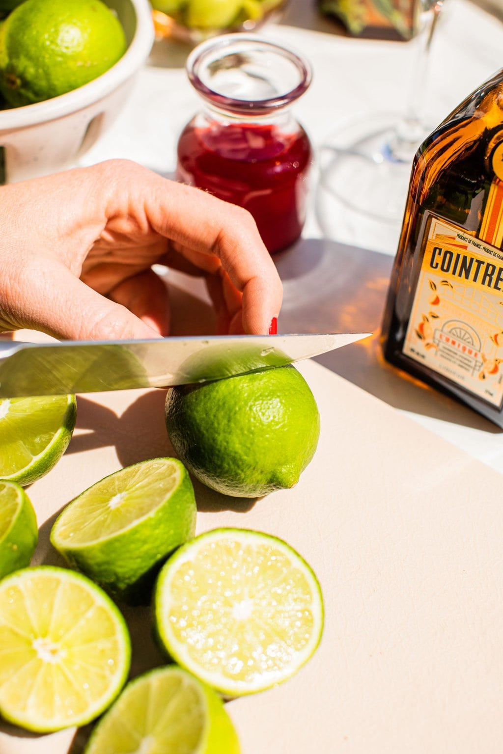 elizabeth chopping limes beside cranberry juice and cointreau