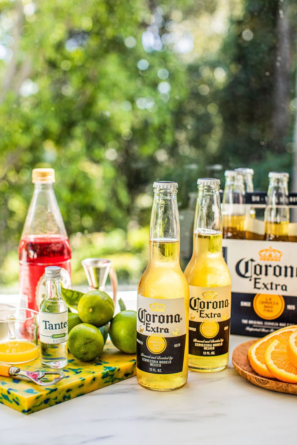 bottles of corona, limes, tequila, grenadine, orange juice, and range slices