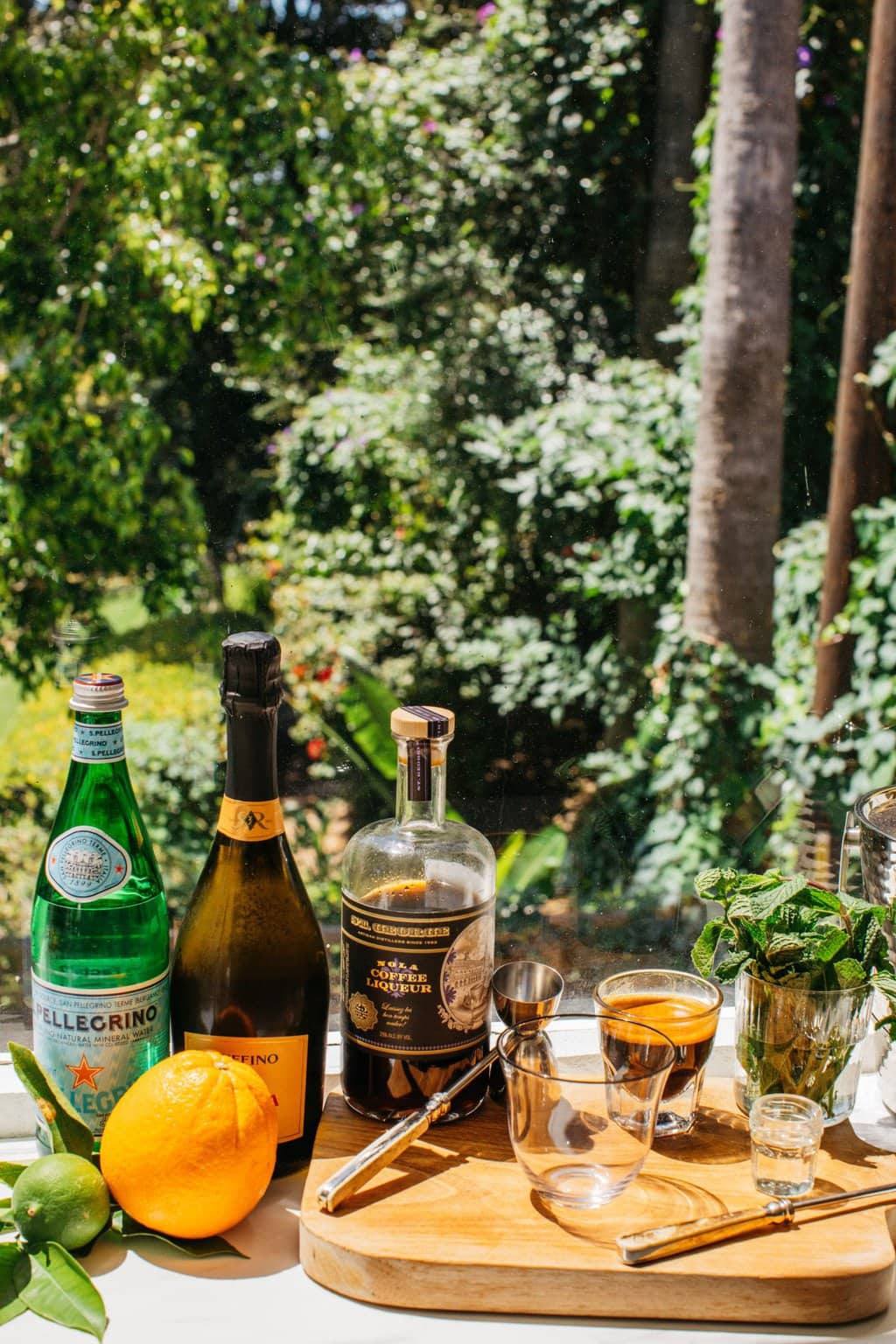 prosecco, Pellegrino, orange, lime, coffee liqueur, and glasses set out to make a spritz