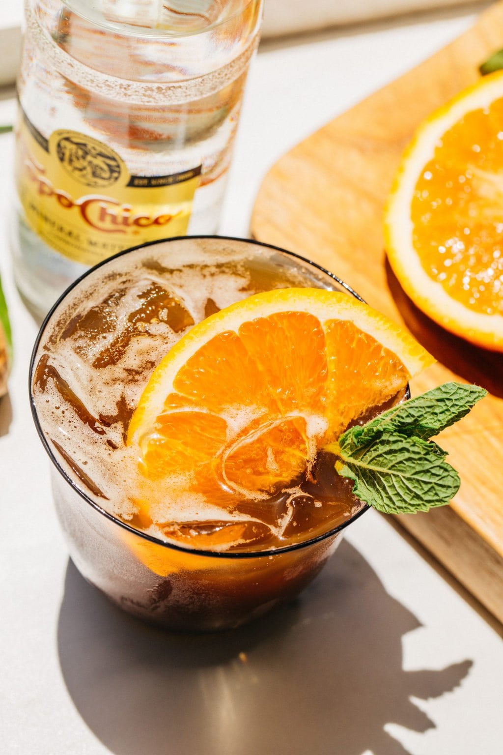 overhead shot of a spritz with orange garnish and a topo chico in the background