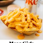 frozen french fries in air fryer with cheese sauce poured on top and text overlay