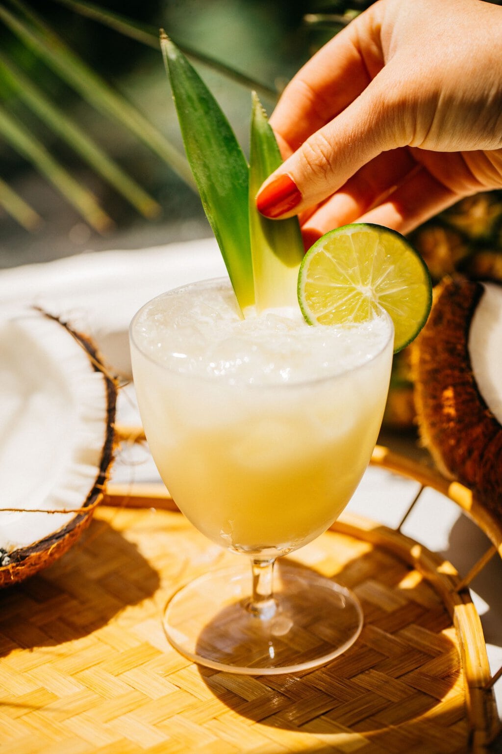 a spritz being garnished with pineapple leaves and a lime wedge