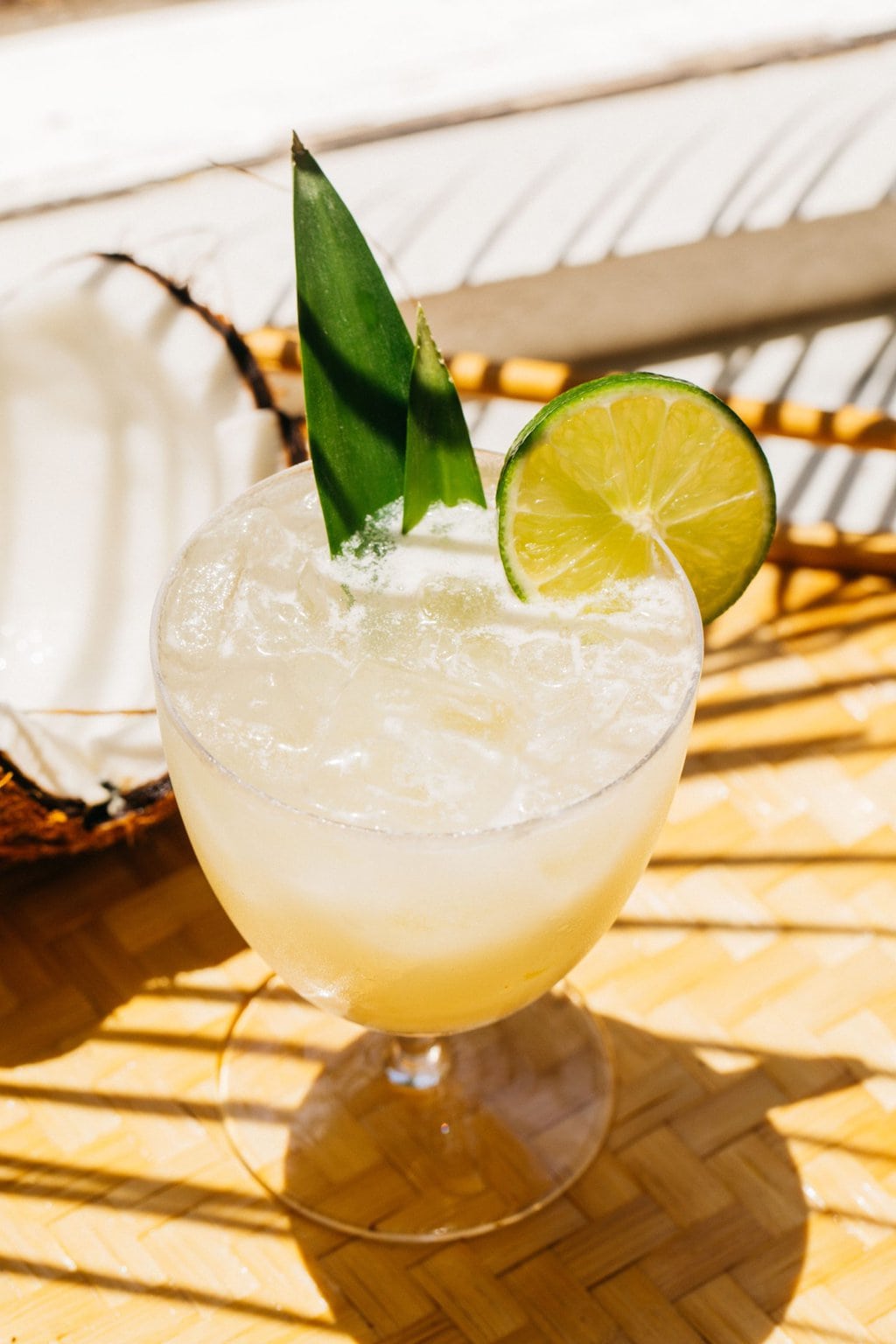 a spritz on a wooden surface with pineapple leaves and a wheel of lime 