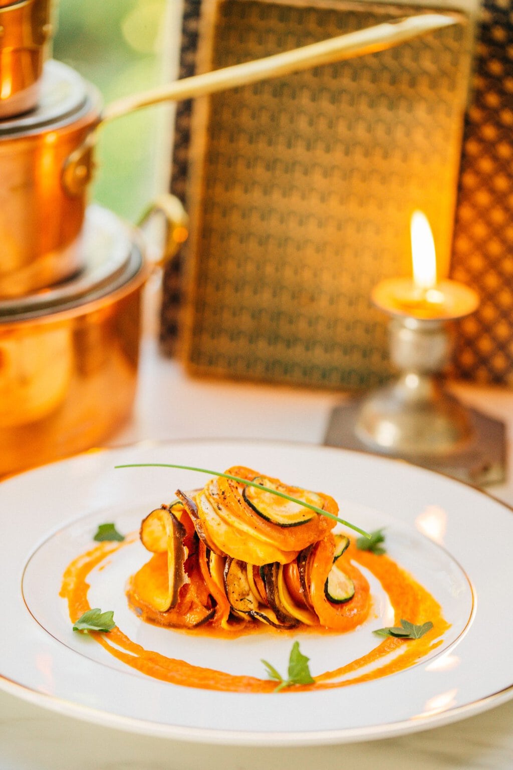 a serving of vegetables on a white plate with sprigs of herbs on top and the sauce drizzled around the pile in a circle