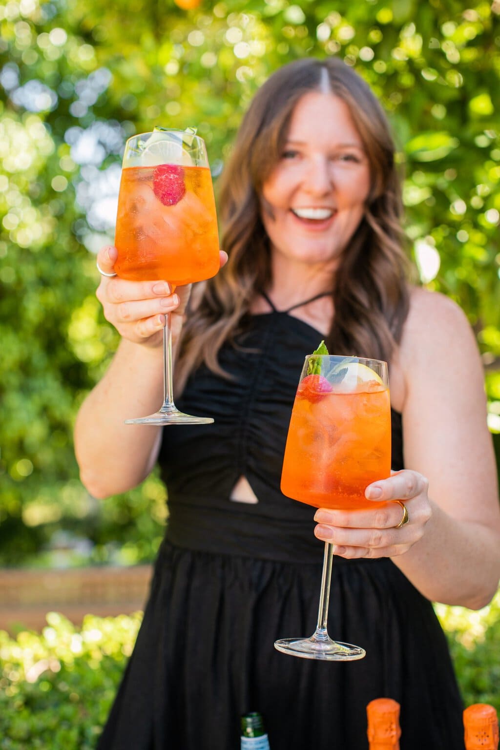 elizabeth holding up two glasses of aperol spritz