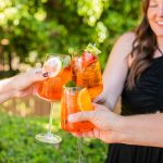 Elizabeth clinking glasses with two other people's aperol spritz'