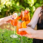 three people clinking glasses of aperol spritz together