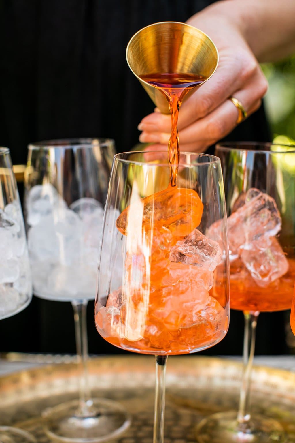 pouring the aperol into a glass with ice in it