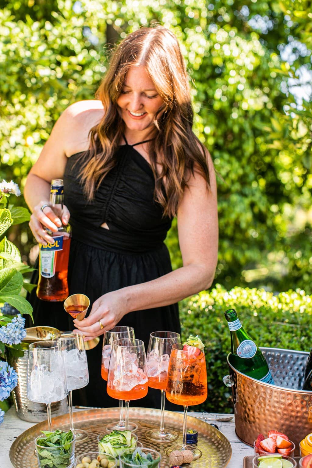 elizabeth pouring aperol into glasses set out on a gold serving platter