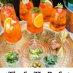 a gold platter with 6 glasses of aperol spritz on it, along with text overlay