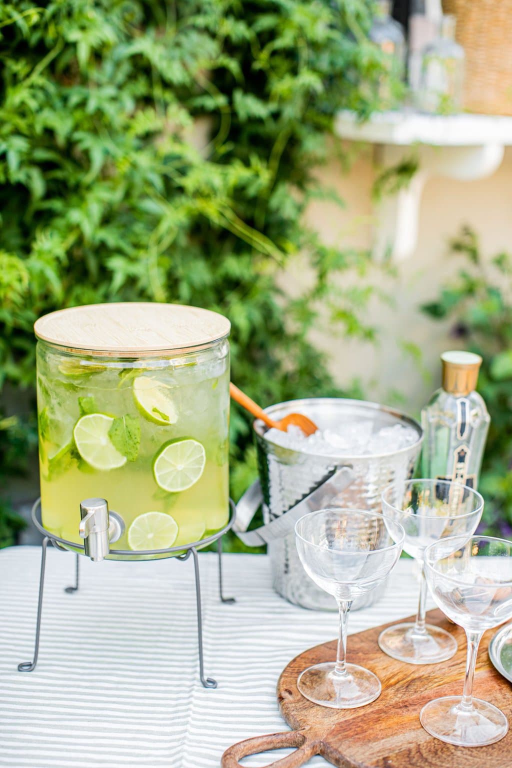 a large pitcher of a hugo spritz with an ice bucket and glasses beside it