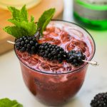 a blackberry gin spritz garnished with blackberries and mint
