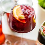 A pomegranate spritz with lambrusco garnished with an olive slice