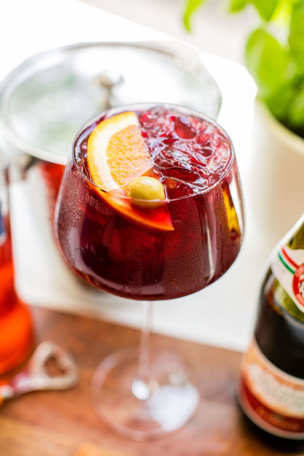 A pomegranate spritz with lambrusco garnished with an olive slice