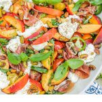 a bowl full of peach burrata salad with text overlay