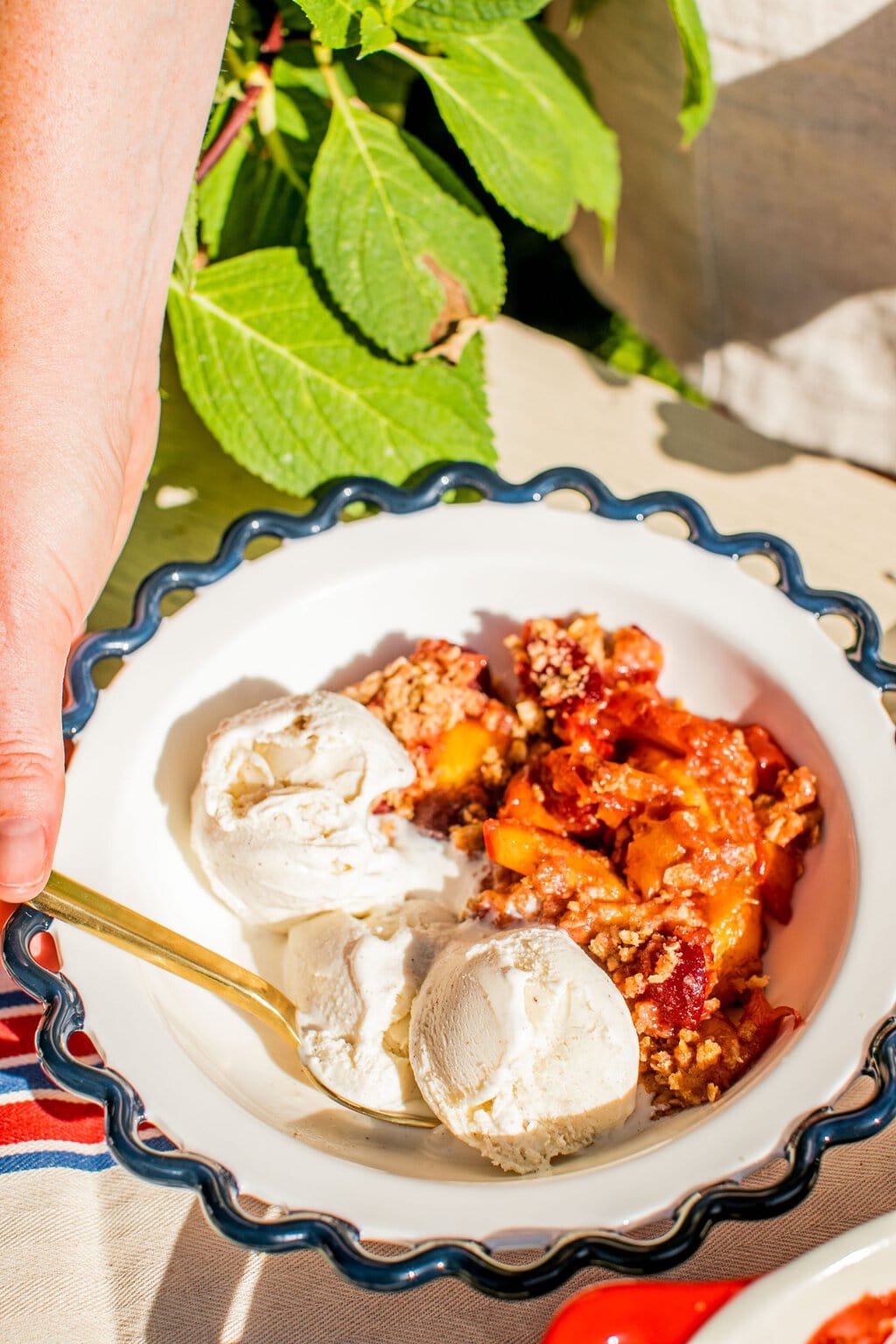 a bowl of fruit crisp with vanilla ice cream and a golden spoon in the side of the bowl