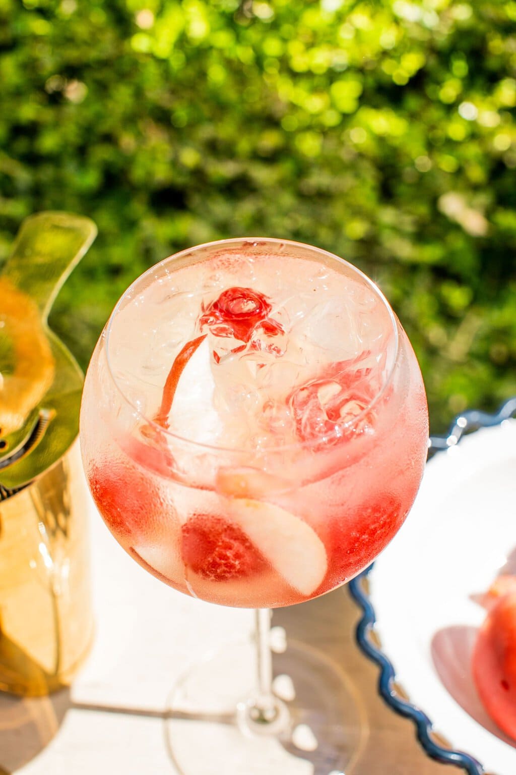 an overhead shot of a peach spritz in a white glass with peach slices and raspberries