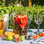 a large pitcher full of sangria with figs, oranges, and other fruits scattered around