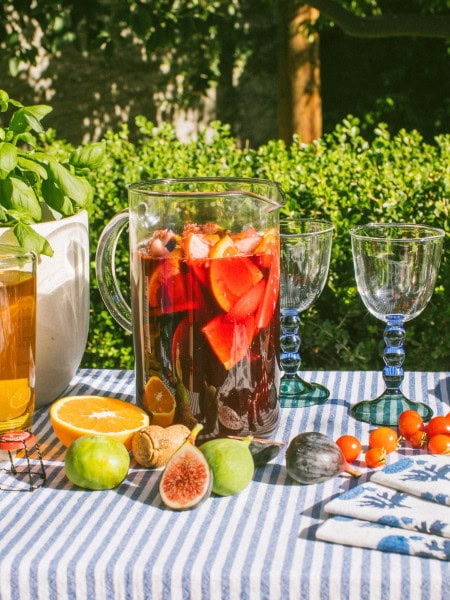 a large pitcher full of sangria with figs, oranges, and other fruits scattered around