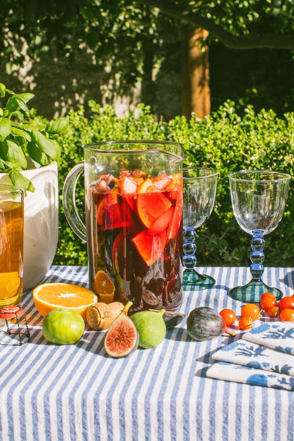 a large pitcher full of sangria with figs, oranges, and other fruits scattered around