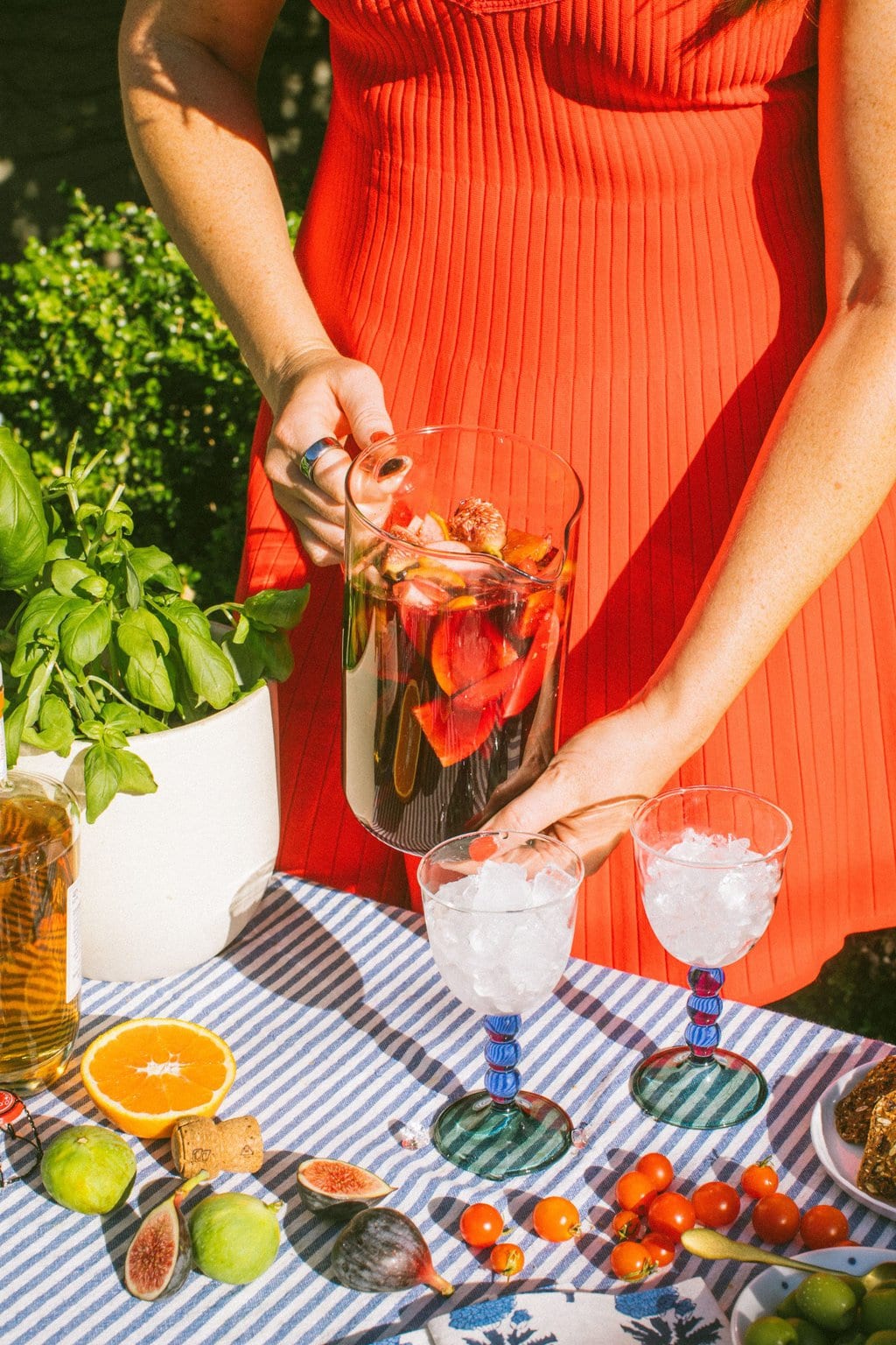 elizabeth pouring a pitcher of lambrusco sangria into two glasses of ice