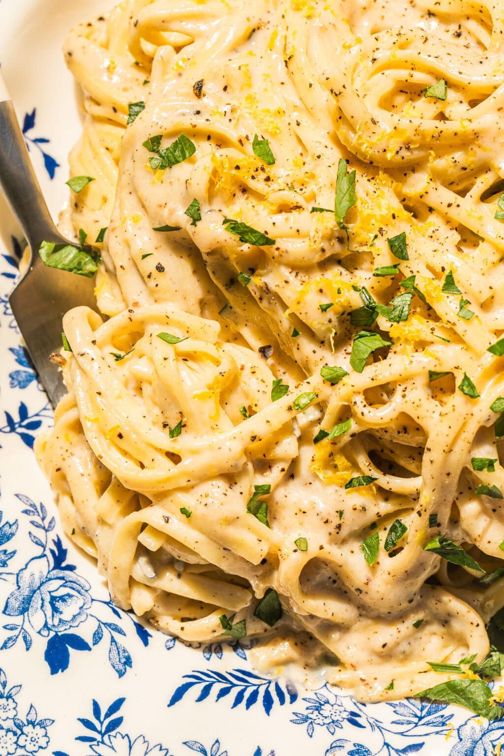 close up photo of lemon pasta with a creamy sauce and green garnish